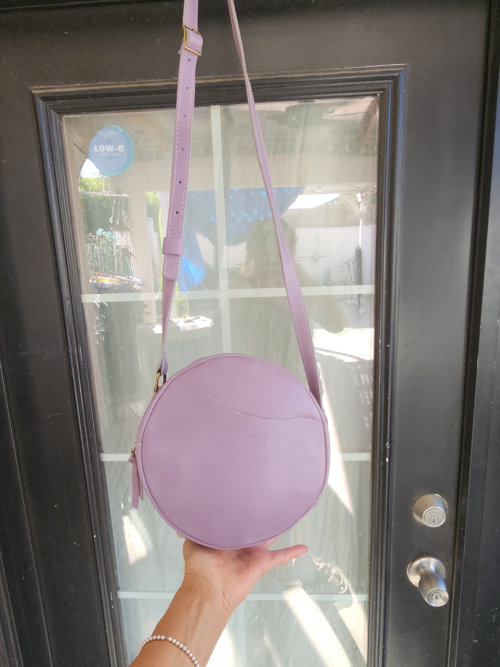 The purple round bag in the image is a Circle Crossbody in the color Lavender - Picture 6 of 8